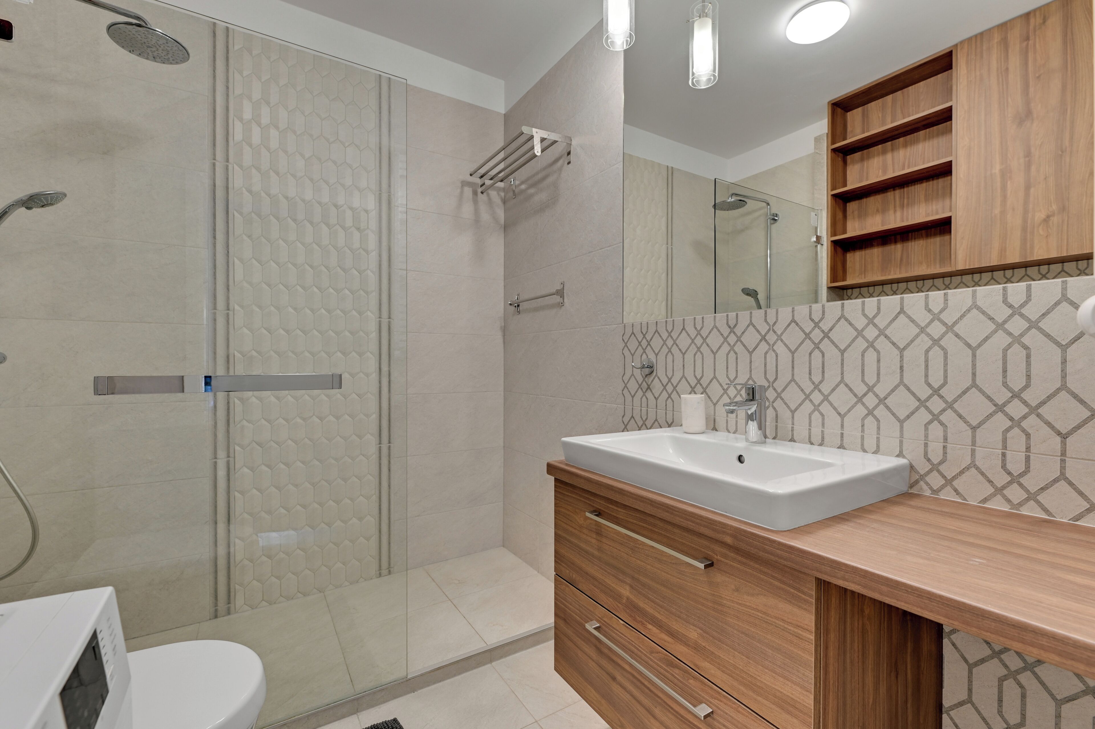 A modern bathroom with a glass-enclosed shower, a wooden vanity with a sink, and a mirror above the vanity.