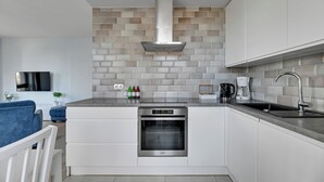 A modern kitchen with white cabinetry, a stainless steel oven, a built-in range hood, and a tiled backsplash. - Okrzei Residence - Nadmorska Bryza by GA (Sopot)