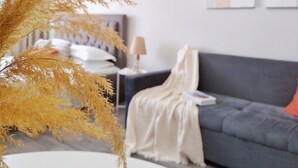 A modern living room with a grey sofa, a white vase with dried plants, and two framed artworks on the wall. - Cozy "Spica" apartment with mountain view in Almaty + AC, WiFi (Almaty)