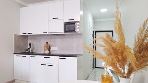 A modern kitchen with white cabinets, a microwave, and a sink. There is a vase with dried plants on the counter. - Cozy "Spica" apartment with mountain view in Almaty + AC, WiFi (Almaty)