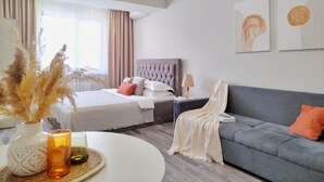 A modern hotel room with a bed, a sofa, a bedside table with a lamp, and artwork on the wall. - Cozy "Spica" apartment with mountain view in Almaty + AC, WiFi (Almaty)