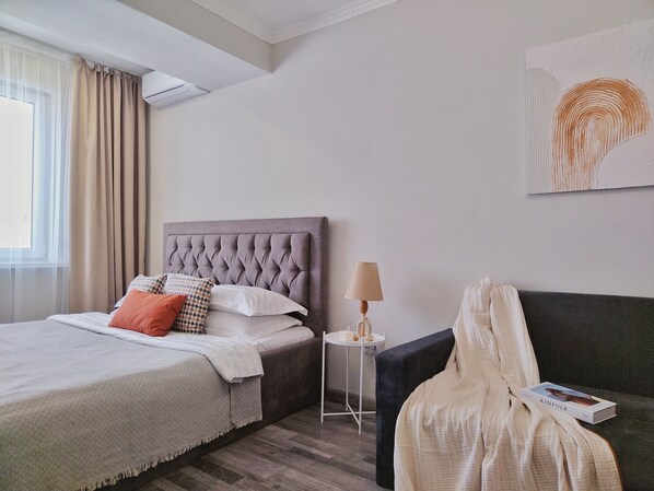 Une chambre d’hôtel avec un lit, une table de chevet, une lampe et un livre sur le canapé.