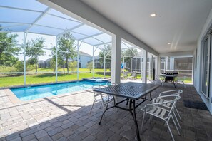 Un espace extérieur abrité comprenant une piscine, du mobilier de jardin et un barbecue.