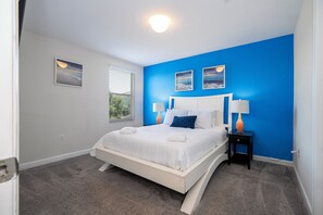 A bedroom with a white bed, blue accent walls, and two bedside lamps. - Spacious Themed 8BR Villa at Champions Gate – Resort full Access, Near Disney! (Four Corners)