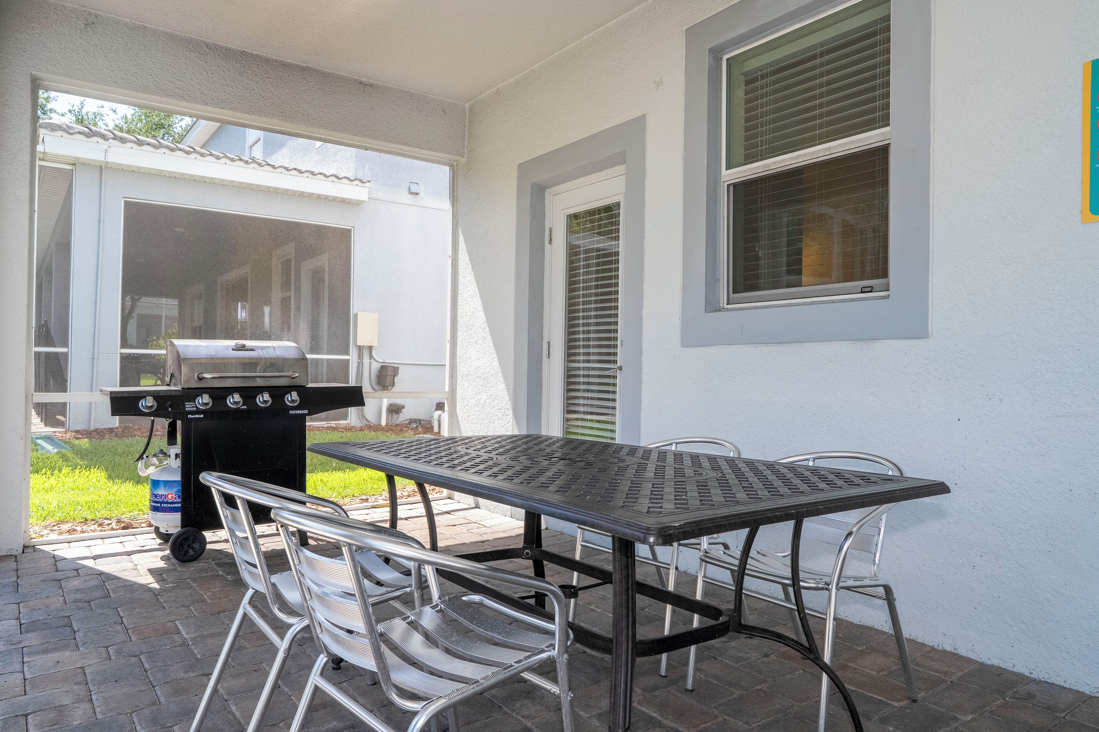 Un patio con una mesa y sillas de metal, una parrilla y un dispensador de agua.