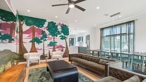 A modern living room with a large sofa, a coffee table, and a dining area with chairs and a table. - The Revelry (New Orleans)