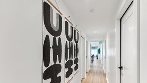 A hallway with large abstract wall art, wooden flooring, and a door on the right. - The Revelry (New Orleans)