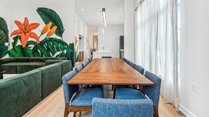 A modern meeting room with a wooden table, blue upholstered chairs, and a green sofa. - The Revelry (New Orleans)