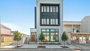 A modern two-story building with a flat roof, large windows, and a small porch. - The Revelry (New Orleans)