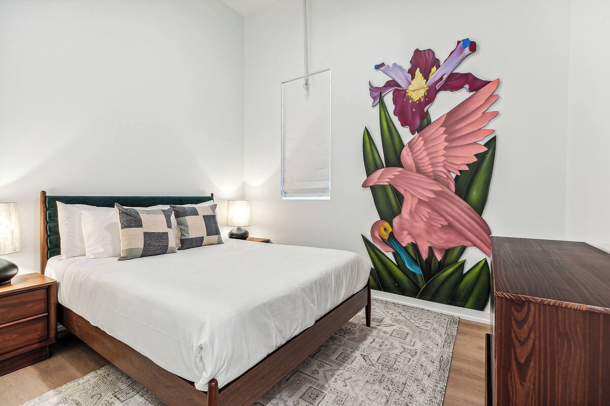 A bedroom with a bed, nightstands, a lamp, a wall-mounted picture, and a wooden dresser.