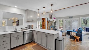 A modern kitchen with grey cabinets, a large island, and pendant lighting.