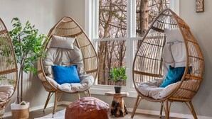 A cozy room with wicker chairs, a wooden stool, and a large leather ottoman.