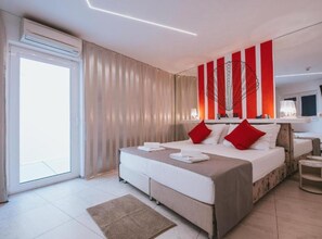 Habitación de hotel moderna con una cama grande, una mesita de noche, un espejo y vistas al exterior.