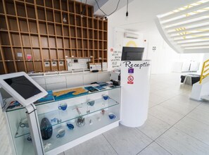 A reception area with a glass display case containing various items, a reception desk, and a wall-mounted TV.