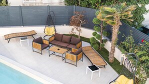 A poolside area with a sofa set, a hanging chair, and a small table. - Bed in Eight Bed Mixed Dormitory Room 2 (Novalja)