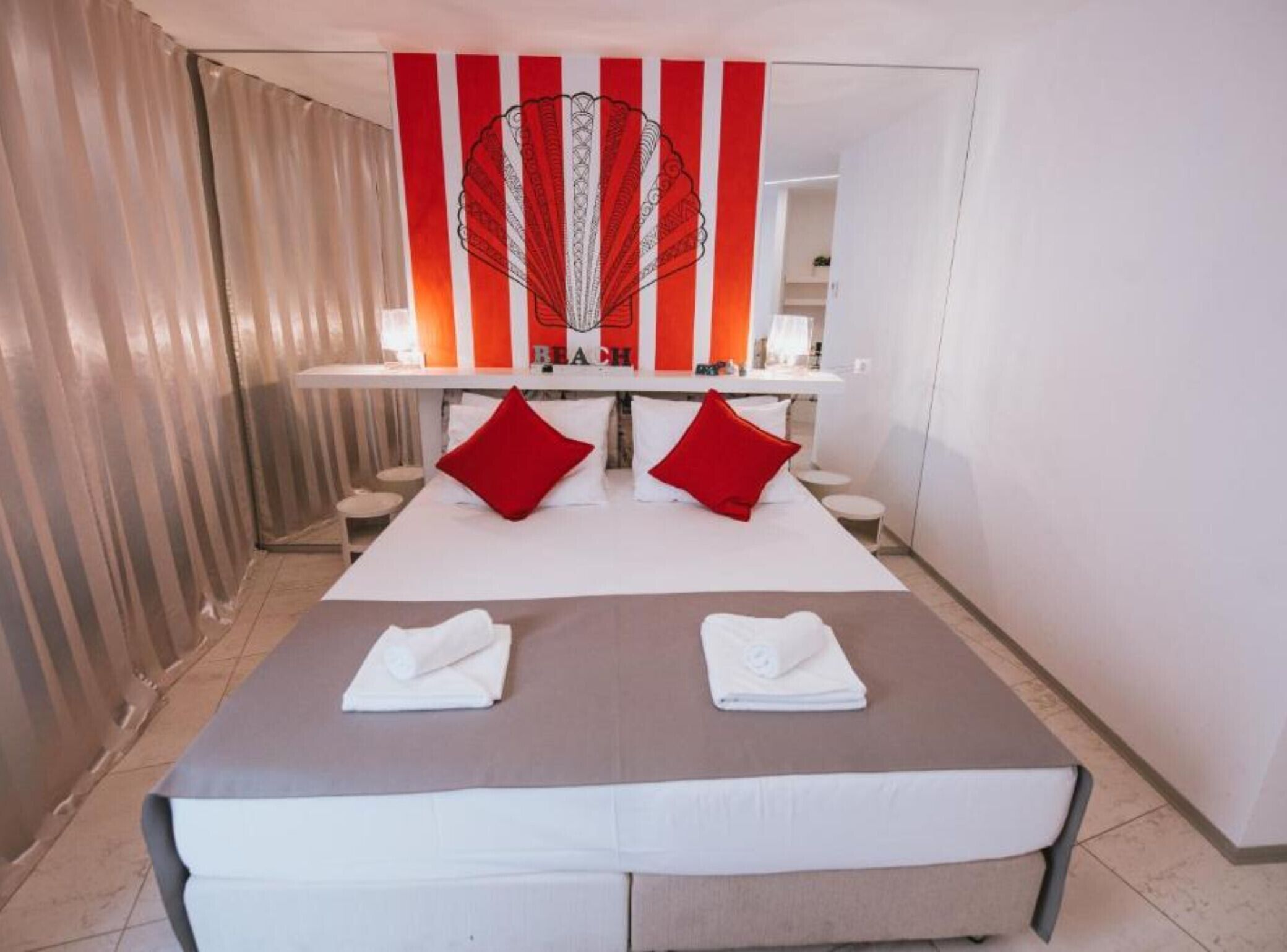Une chambre d’hôtel avec un grand lit, deux oreillers rouges et une serviette sur le lit.