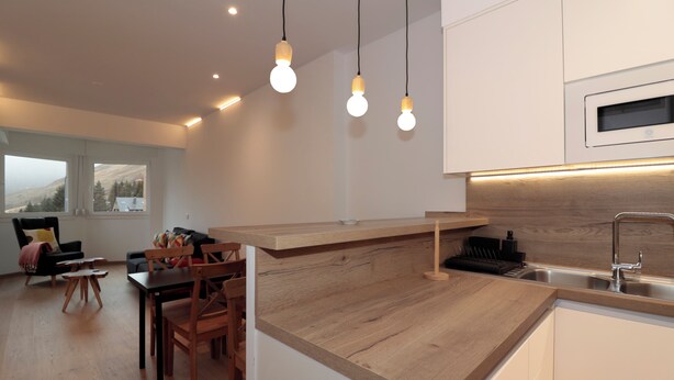 Una cocina moderna con encimeras de madera, horno integrado e iluminación colgante.