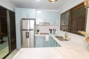 Een koelkast, een microgolfoven, kookgerei, borden en bestek