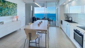 Una cocina moderna con comedor, ventanas amplias y vista al mar.