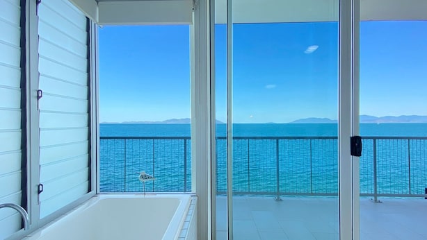 Un balcón con vista al mar y montañas a lo lejos.