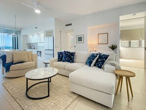 A modern living room with a sofa, coffee table, and a view of the kitchen. - 1 Bright Point Apartment 5101 (Nelly Bay)