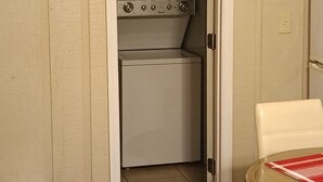 Uma cozinha compacta com máquina de lavar e micro-ondas.