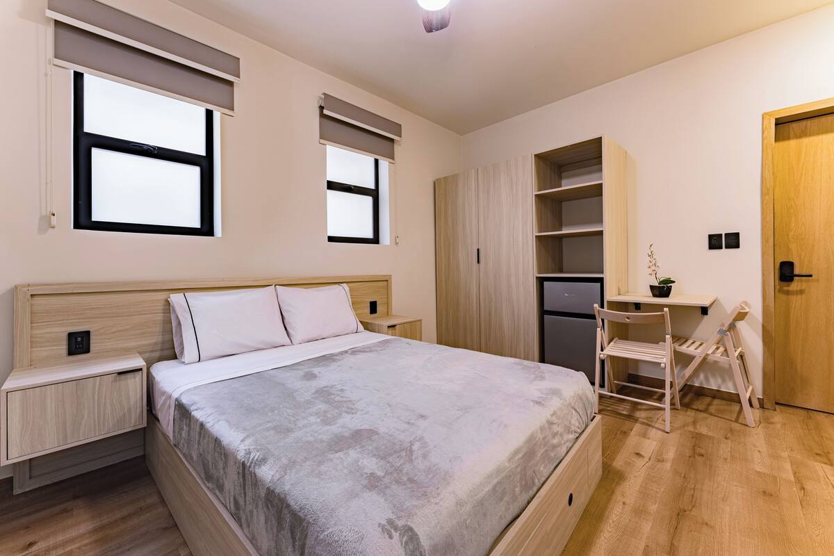 Une chambre à coucher comprenant un lit, des tables de chevet, un bureau et une armoire.