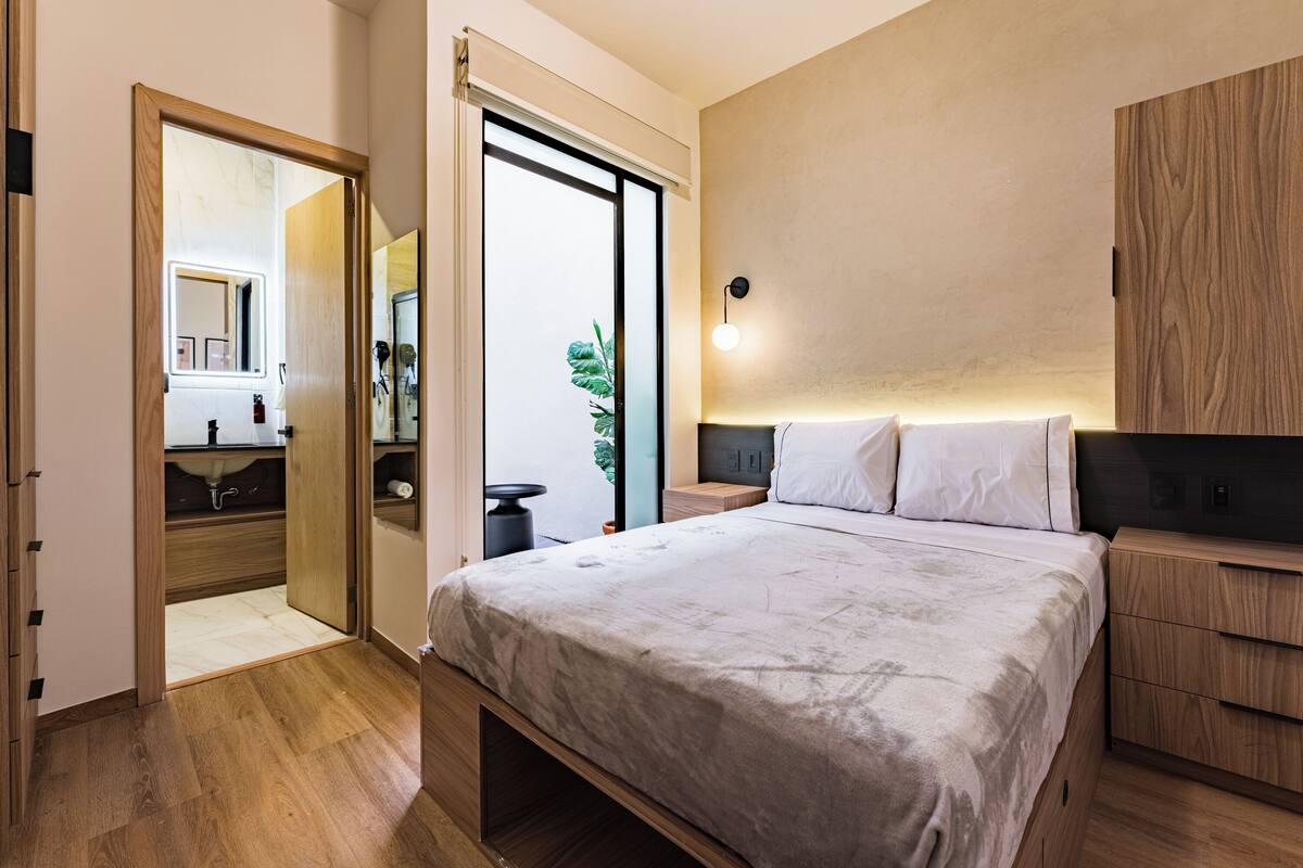 Une chambre à coucher comprenant un lit, des tables de chevet, une commode, un miroir et une armoire.