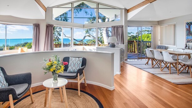 A modern interior with a curved seating area, a dining space, and large windows offering ocean views.