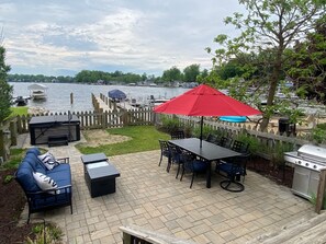 Une terrasse avec des meubles d’extérieur, un barbecue et une vue sur un lac.