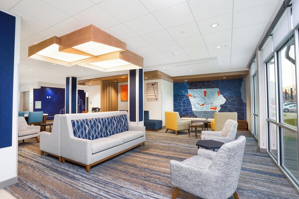 A modern lobby with a sofa, chairs, a coffee table, and a large window. - Holiday Inn Express & Suites Cedar Rapids NE – Marion by IHG (Marion)