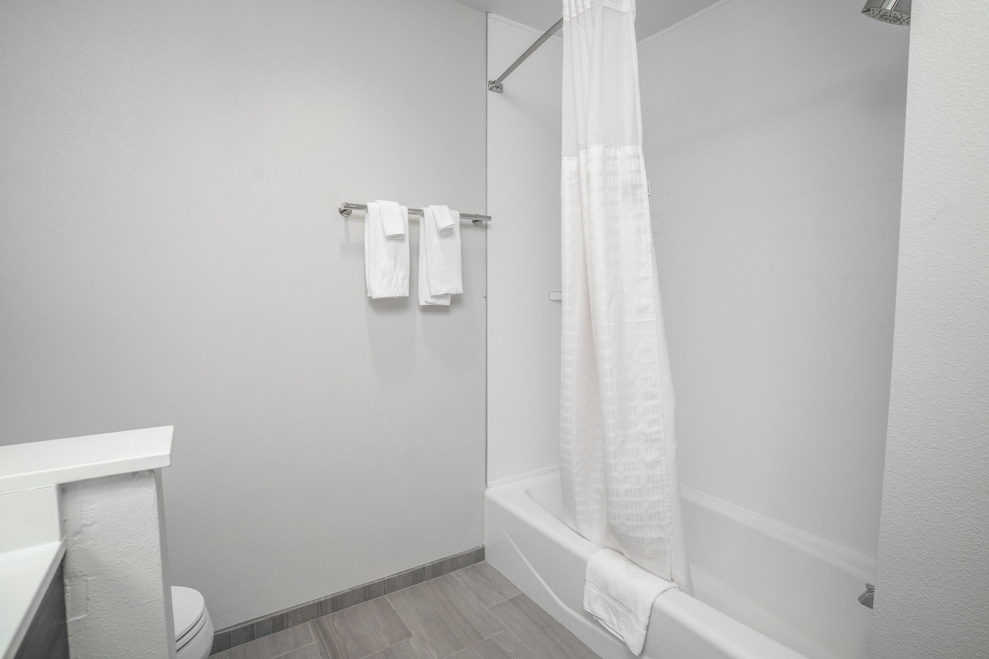 A modern bathroom with a shower, toilet, and a towel rack with two towels.