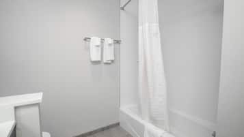 A modern bathroom with a shower, toilet, and a towel rack with two towels.