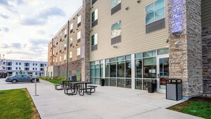 A modern building with a brick facade, large windows, and outdoor seating area. - Holiday Inn Express & Suites Cedar Rapids NE – Marion by IHG (Marion)