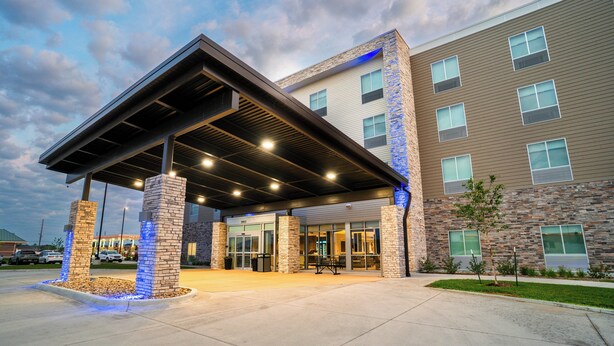 A hotel entrance with a covered walkway, stone pillars, and a parking lot. - Holiday Inn Express & Suites Cedar Rapids NE – Marion by IHG (Marion)