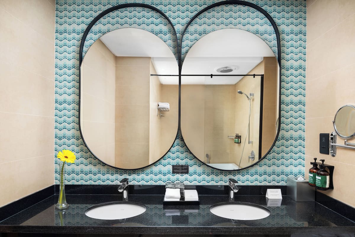 A bathroom with two sinks, a mirror, and a shower.