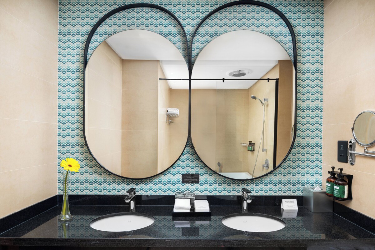 A bathroom with two sinks, a mirror, and a shower.