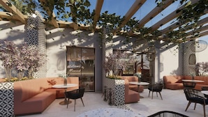 Een terras met comfortabele banken, ronde tafels en hangplanten.