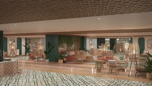 Een ruime lobby met een vloer in een patroon, rieten meubels en groene decoraties.