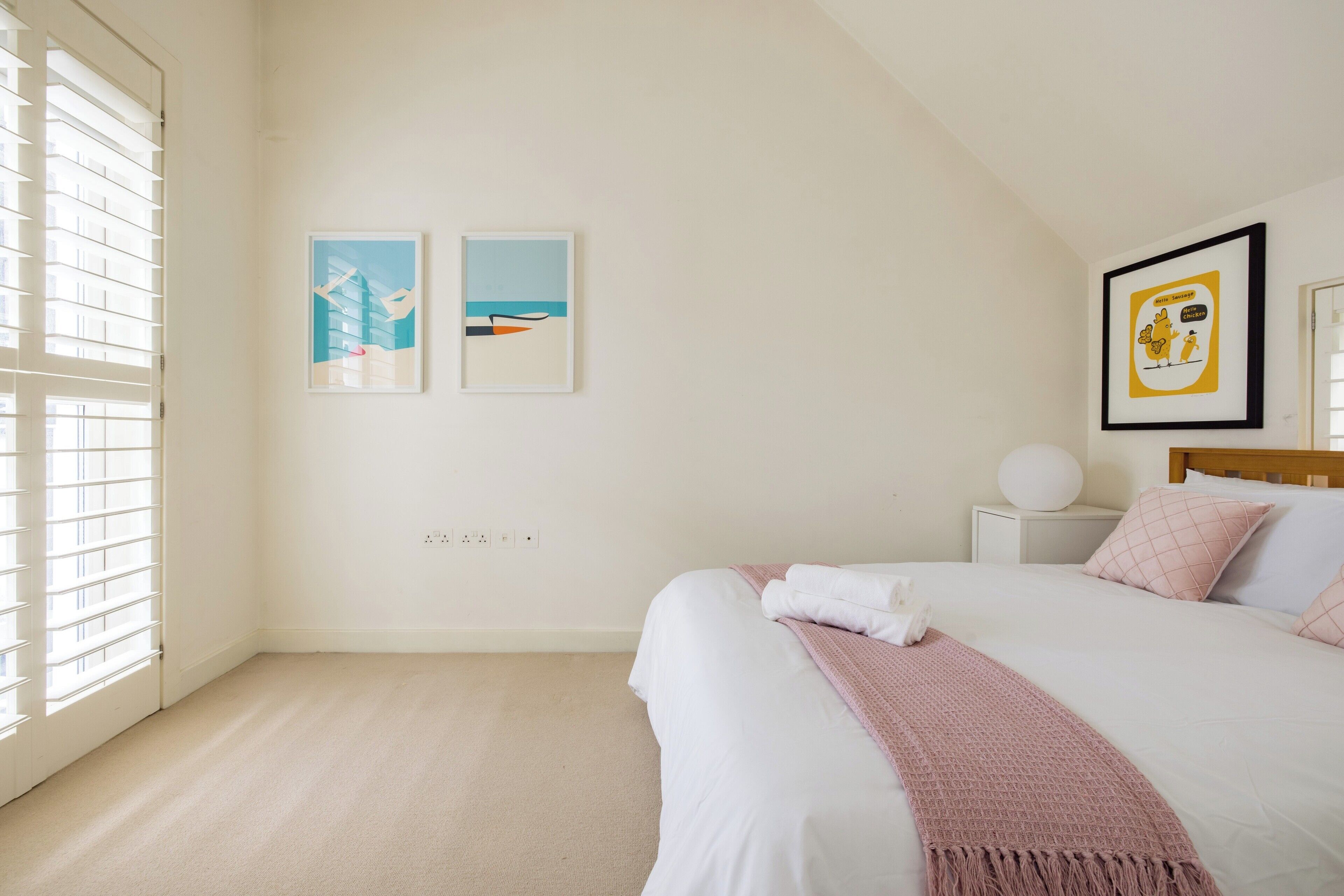 A bedroom with a bed, a bedside table, a nightstand, and a wall-mounted lamp.