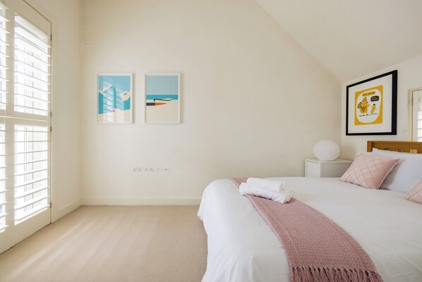 Quarto com cama, mesa de cabeceira e luminária fixada na parede.