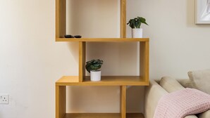 A wooden shelving unit with two potted plants and a pair of black shoes on the top shelf. - The Sakura Mews by Harrods (London)