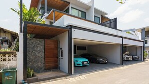 A modern two-story house with a covered garage and two cars parked inside. - The Designer 49 Villa (Bangkok)