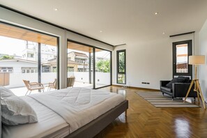 A modern bedroom with a large bed, a sofa, and a view of the city. - The Designer 49 Villa (Bangkok)
