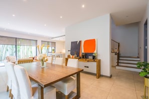 A modern living space with a dining area, a staircase, and a view of the outdoors. - The Designer 49 Villa (Bangkok)