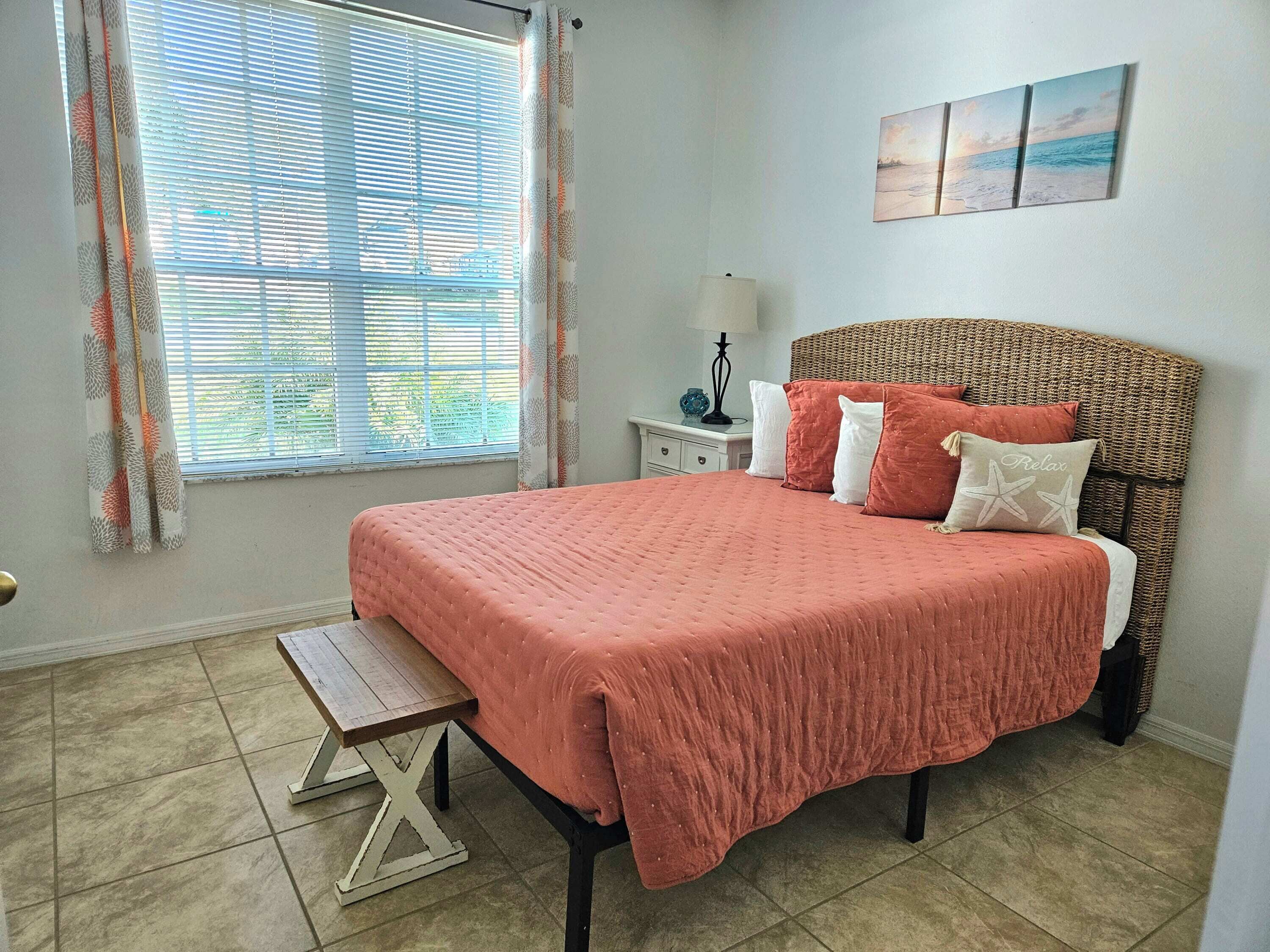 A bedroom with a bed, a nightstand, a lamp, and a window with curtains.