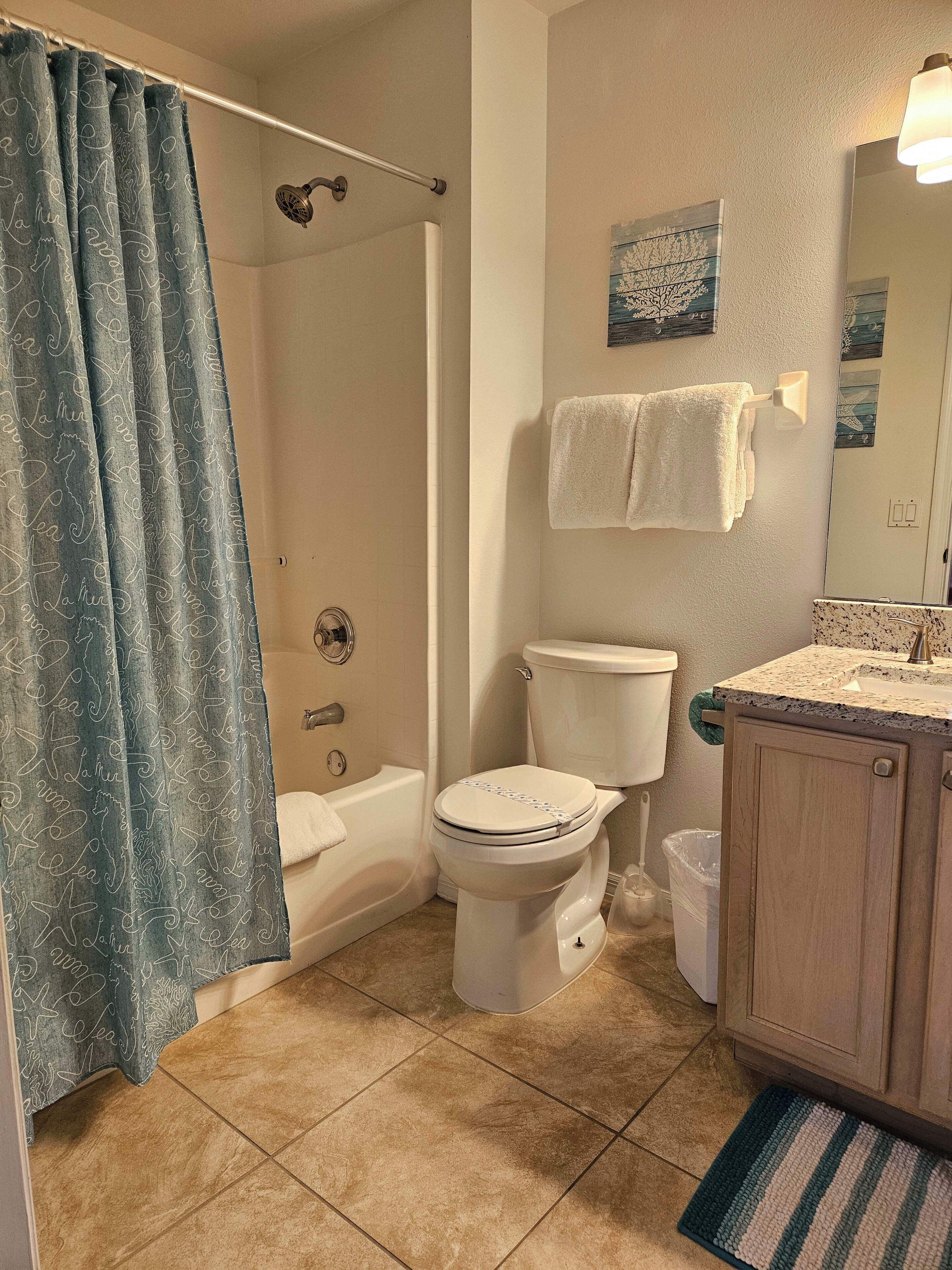 A bathroom with a shower, toilet, and sink.