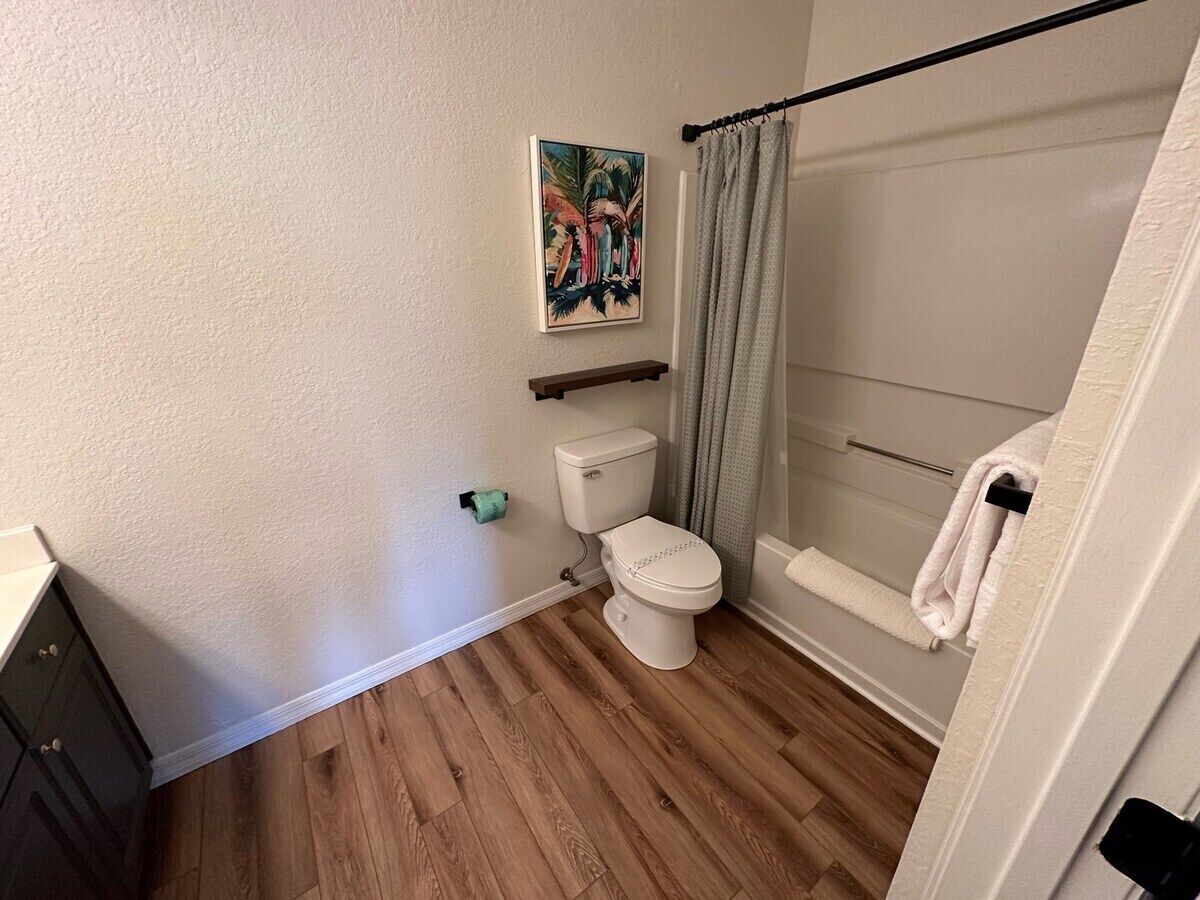 A bathroom with a toilet, shower, and a towel rack.