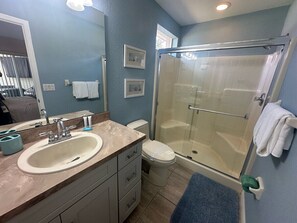 A bathroom with a sink, toilet, and glass shower enclosure.