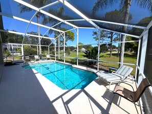 A covered swimming pool with lounge chairs and a view of a residential area. - Beautiful Golf Course Views - Southern Dunes Villa (Haines City)